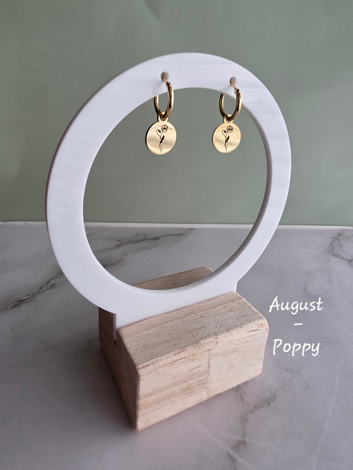 Birth month flower earrings with engraved botanical pendants on gold hoops.