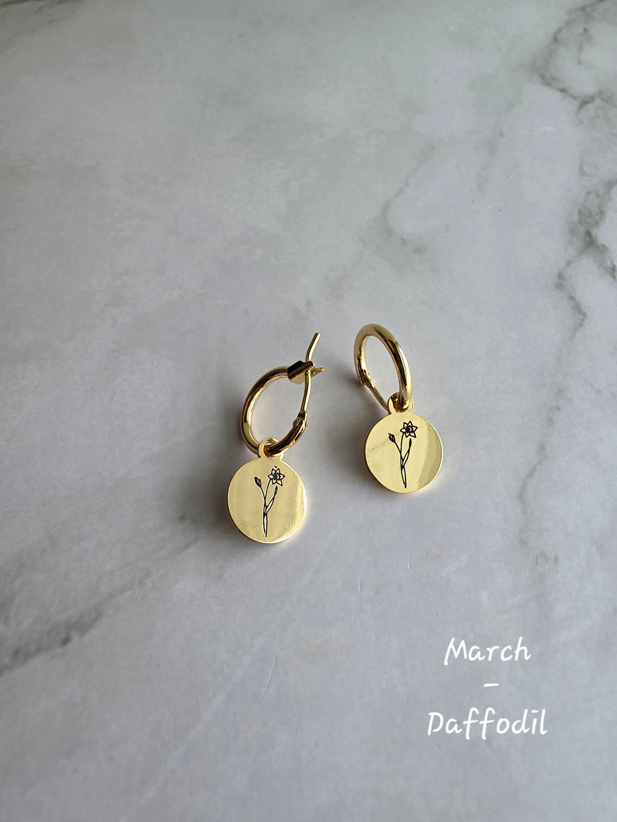 Gold birth month hoop earrings with detailed engraved flower charms.