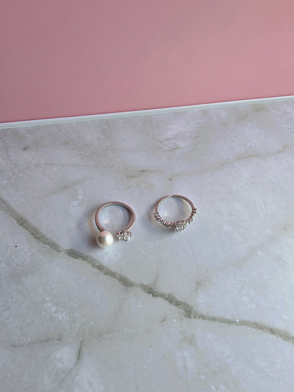 Stackable gold toe rings with pearl, flower, and cubic zirconia embellishments.