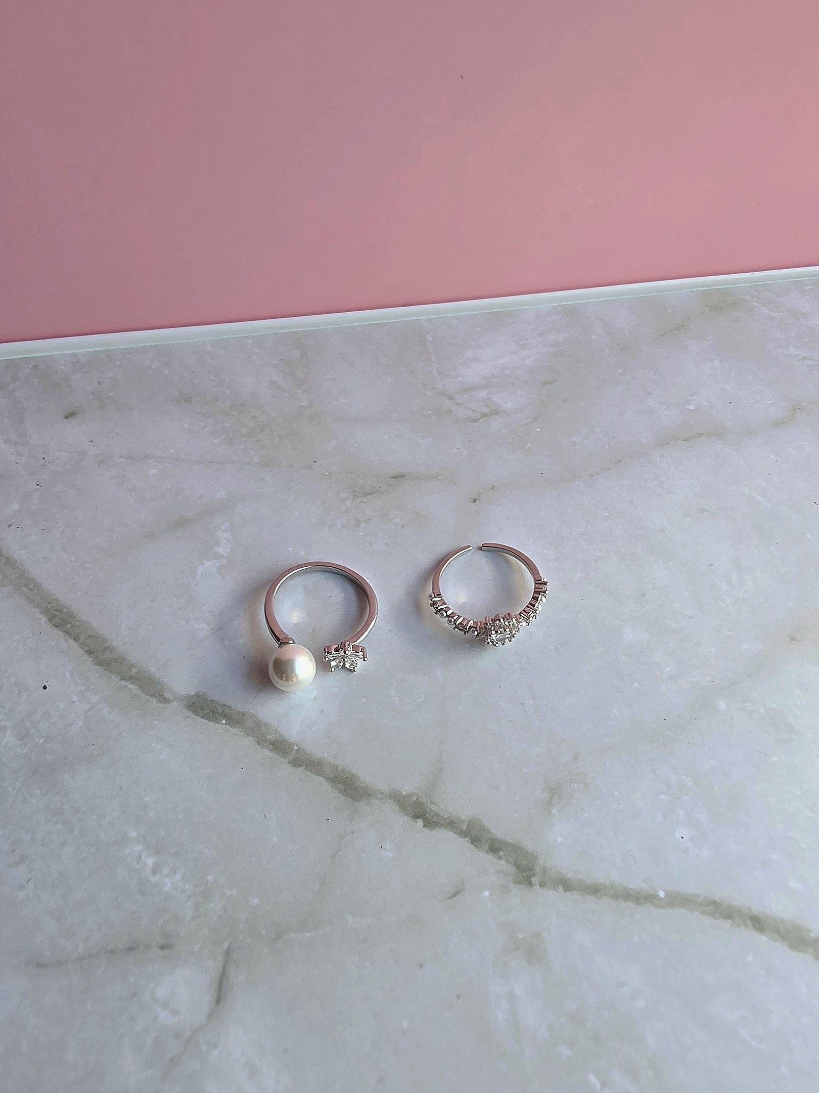Stackable gold toe rings with pearl, flower, and cubic zirconia embellishments.