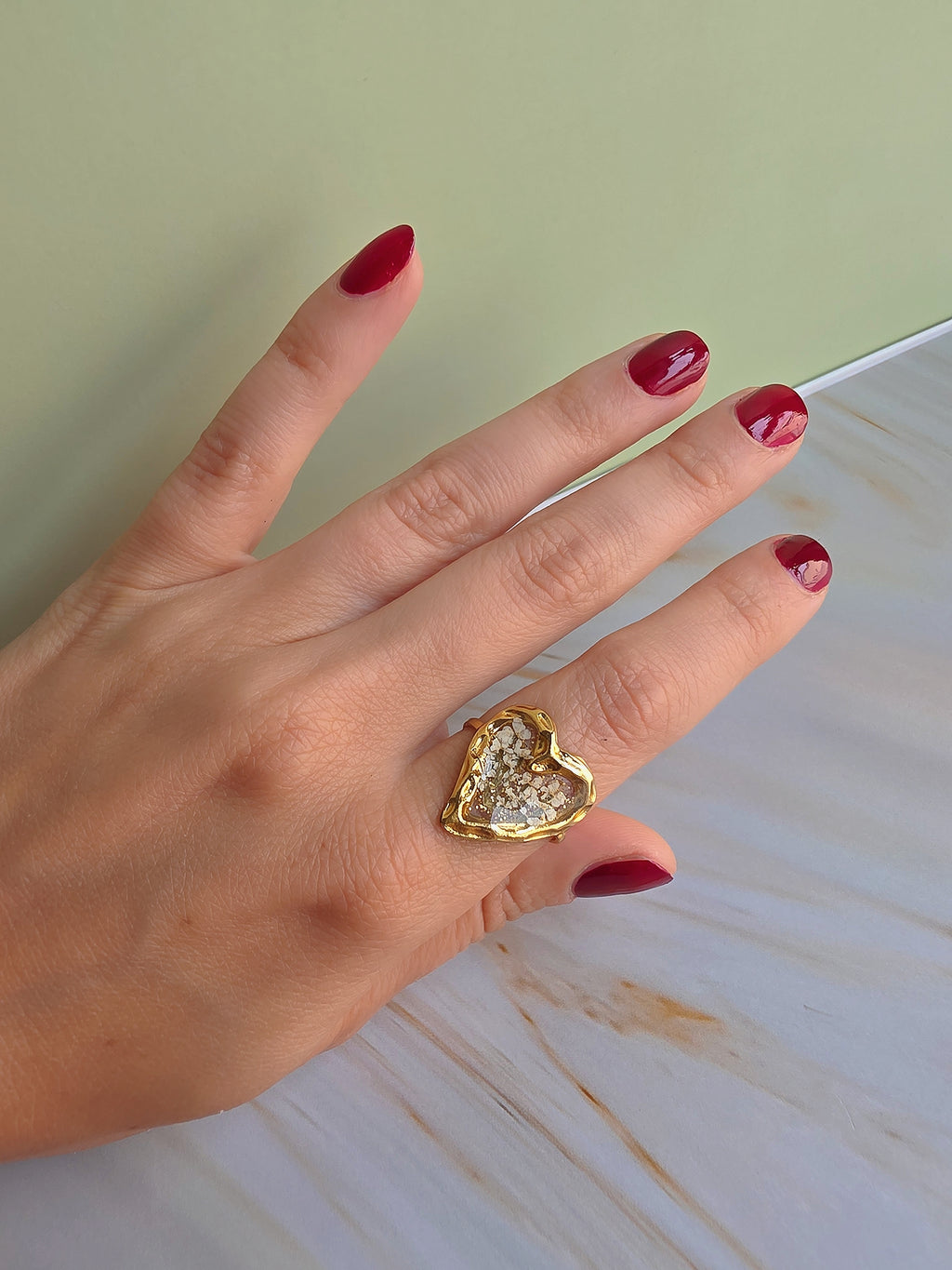 Close-up of an adjustable floral resin ring with delicate dried white flowers.