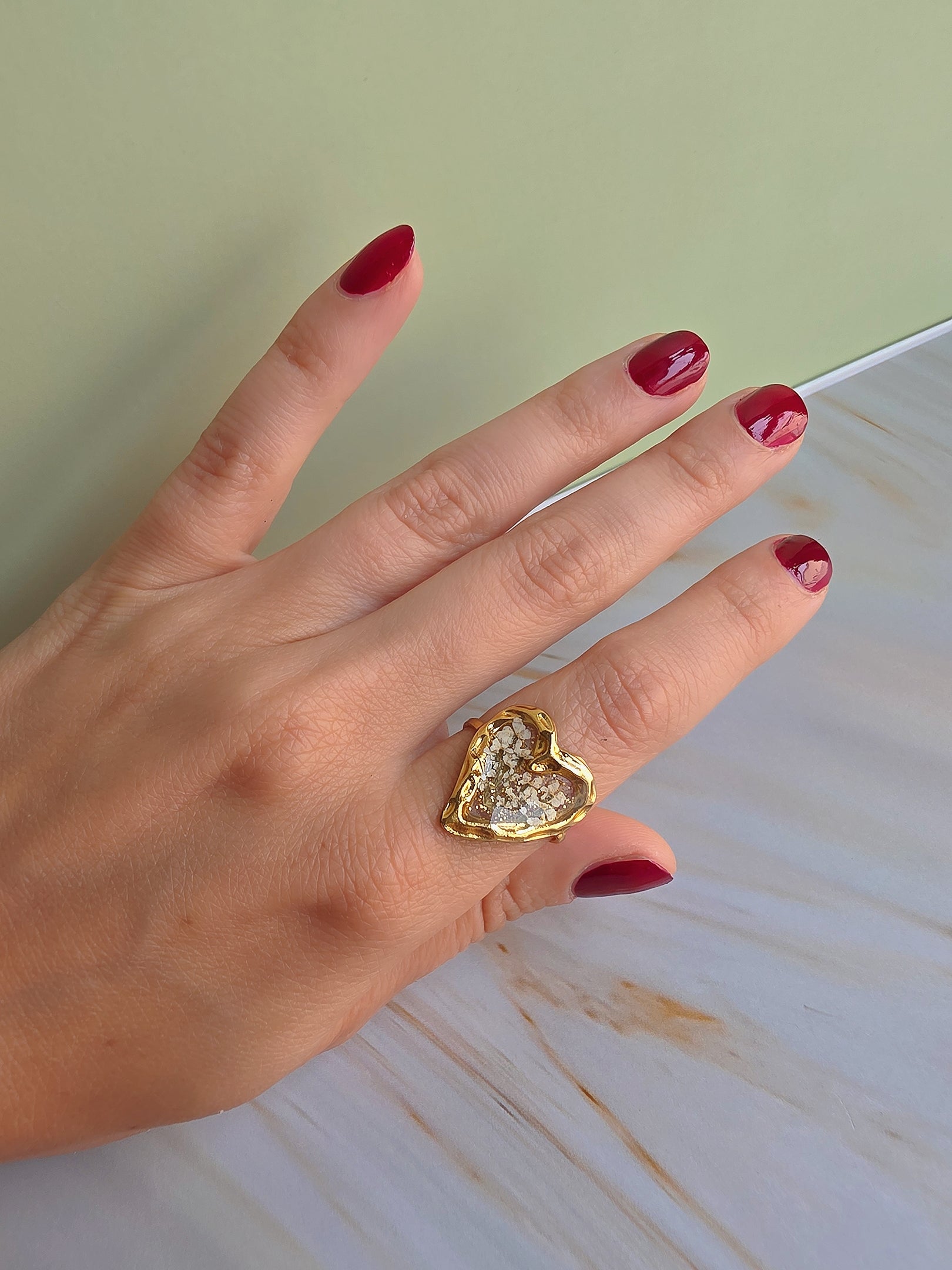 Close-up of an adjustable floral resin ring with delicate dried white flowers.