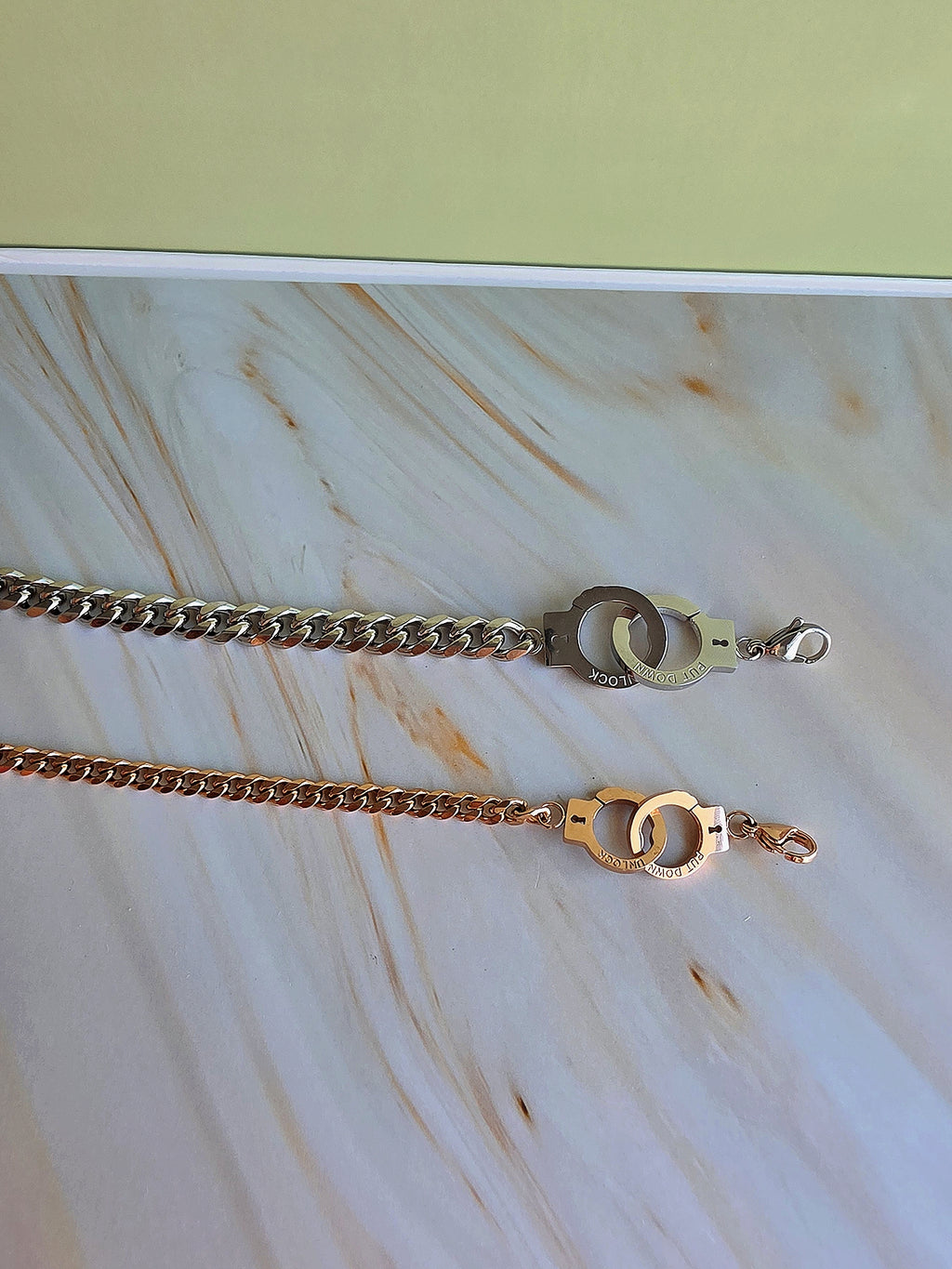 Two gold chains with clasp on a marble surface
