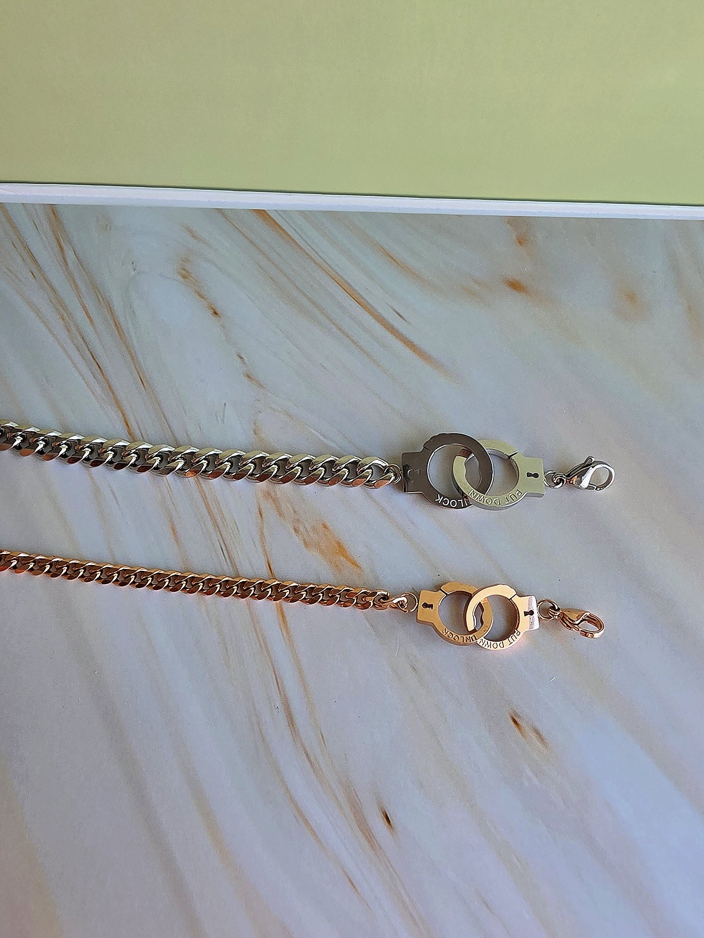 Two gold chains with clasp on a marble surface