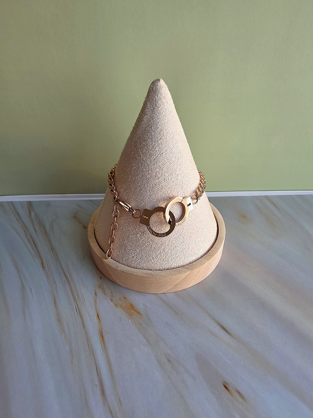 Decorative cone-shaped jewelry holder with gold chains on a marble surface