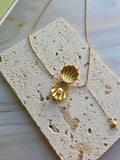 Elegant shell pendant necklace with a pearl charm and polished gold finish.