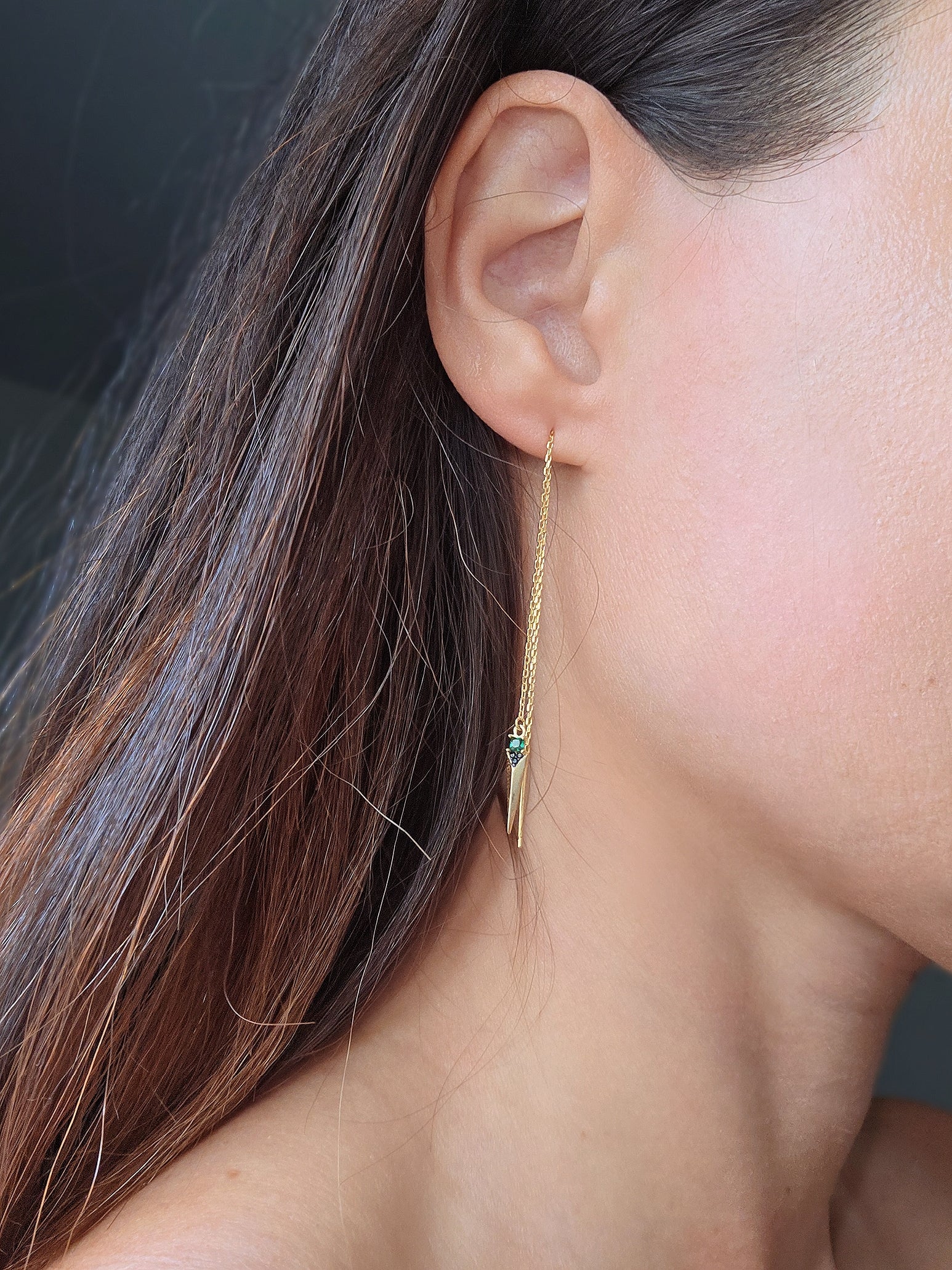 Green emerald threader earrings featuring a polished gold-plated chain and spike charm.