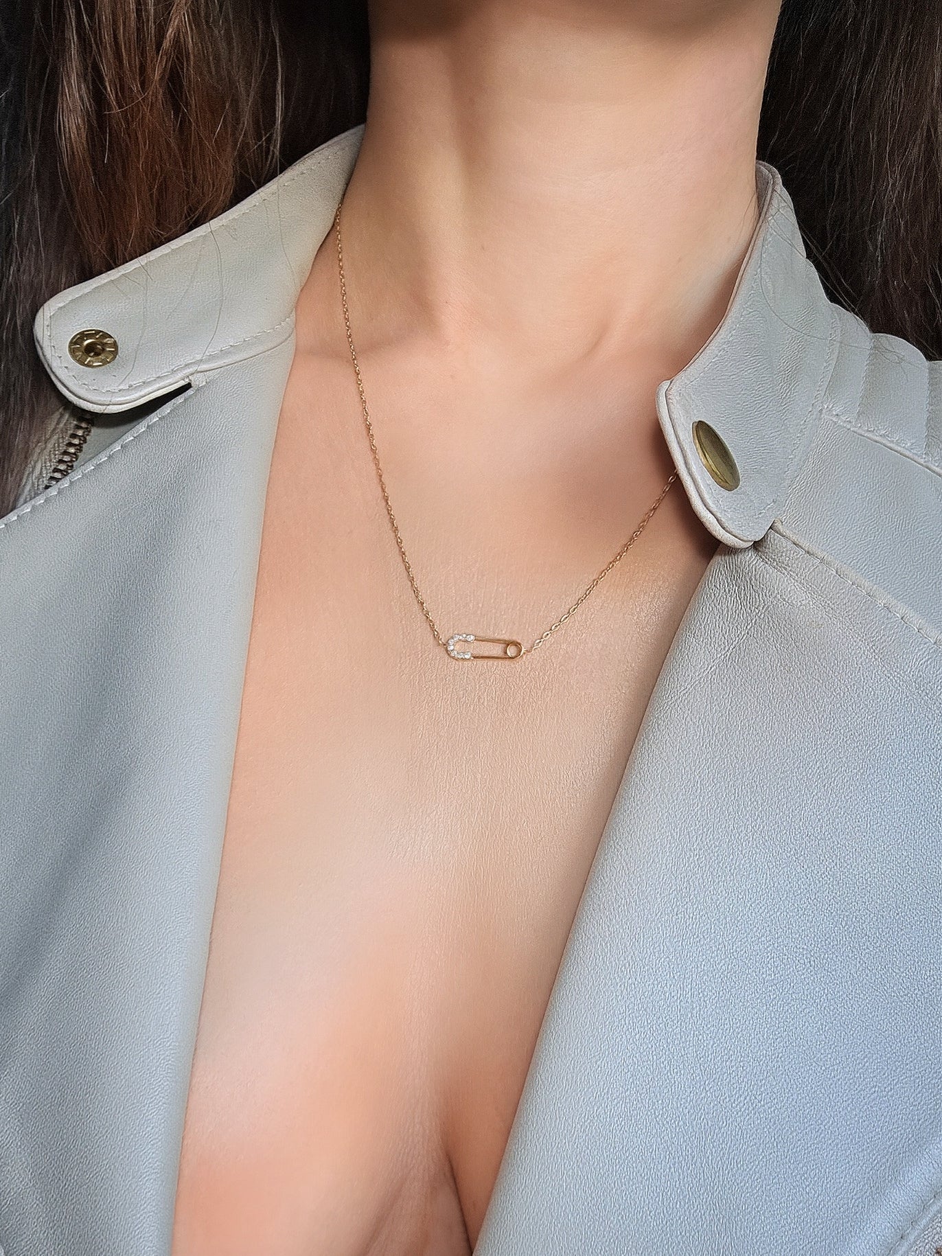 Minimalist safety pin pendant necklace featuring polished 18K gold plating.