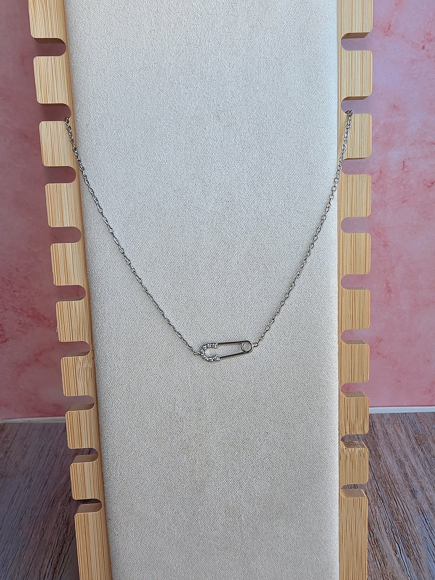 Dainty gold safety pin necklace with a polished finish and crystal accents.