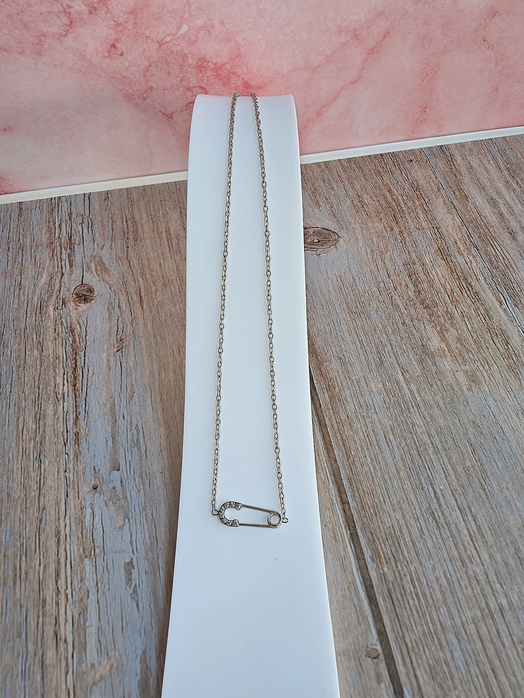 Fashion safety pin necklace crafted with 18K gold plating and cubic zirconia.