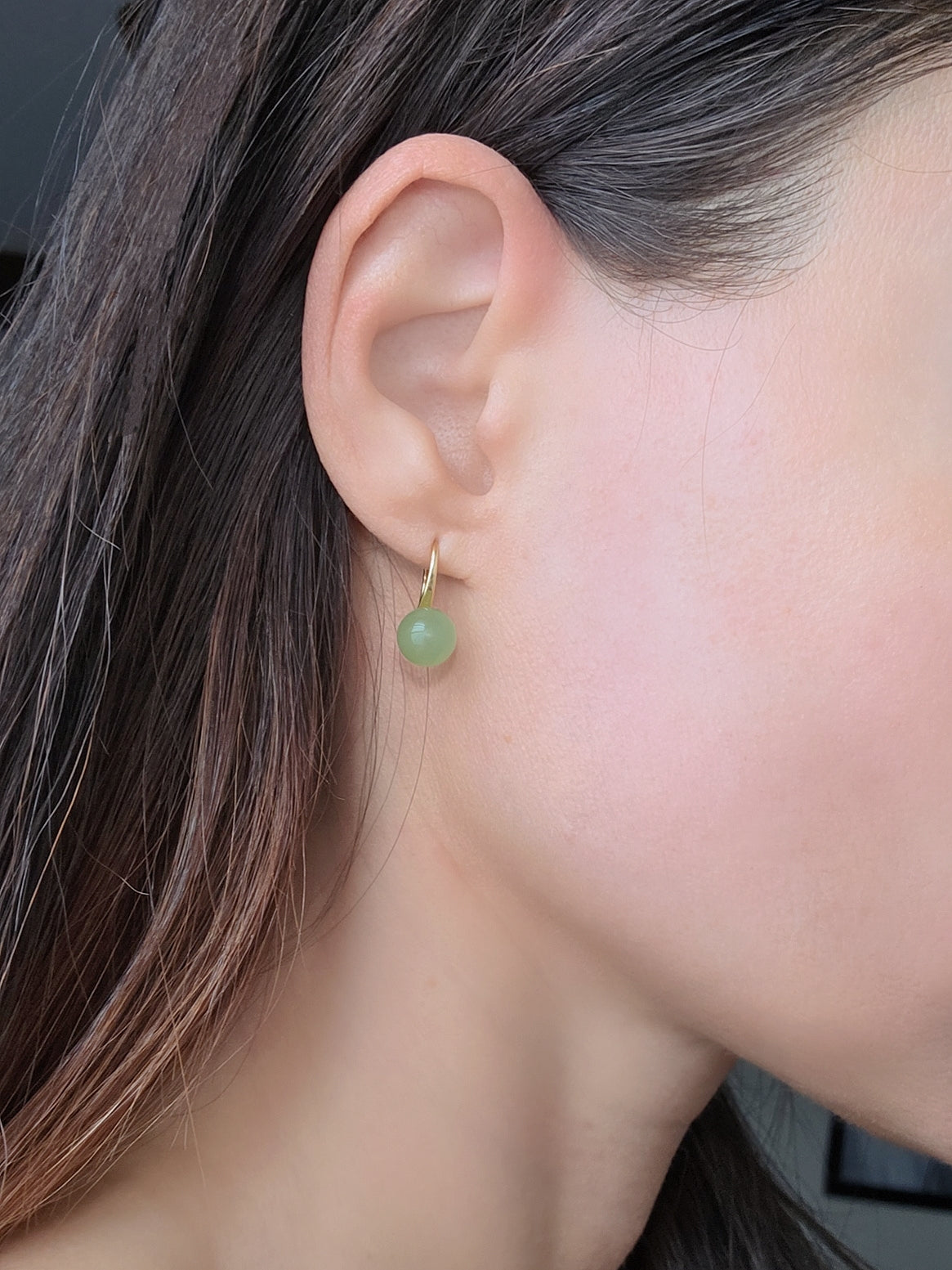 Elegant green jade drop earrings featuring polished 14K gold-plated hooks.