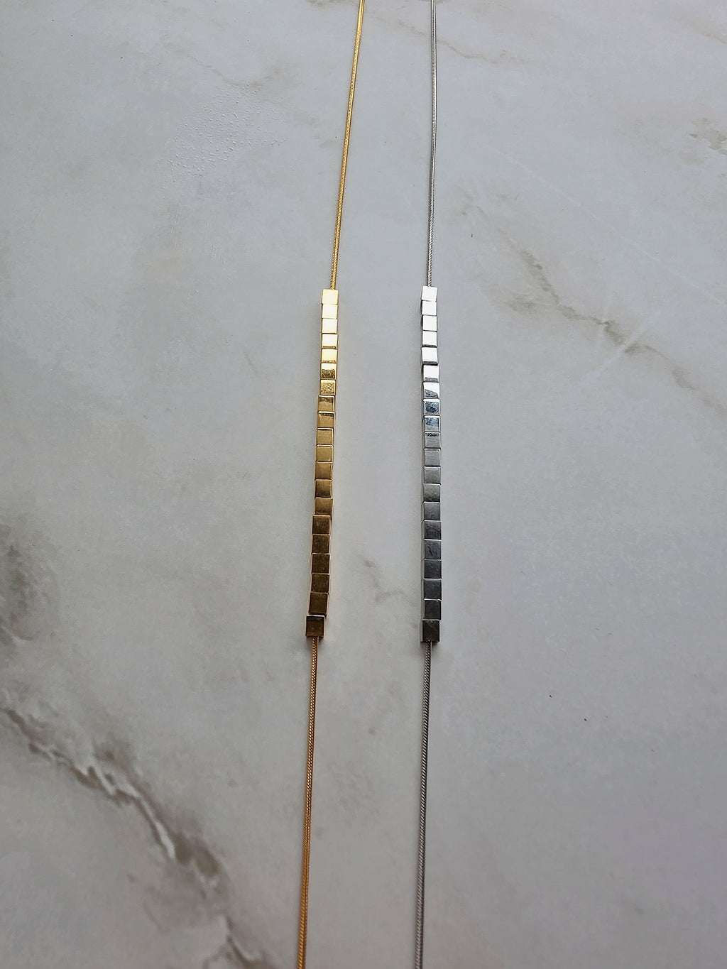 Minimalist 18K gold-plated necklace featuring a rotating cube bead pendant.