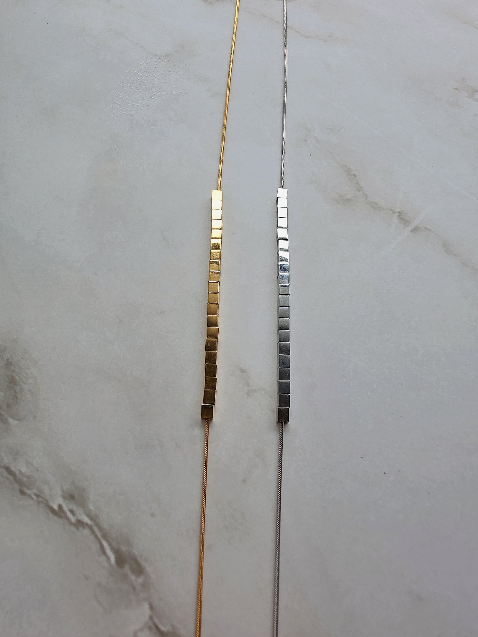 Minimalist 18K gold-plated necklace featuring a rotating cube bead pendant.