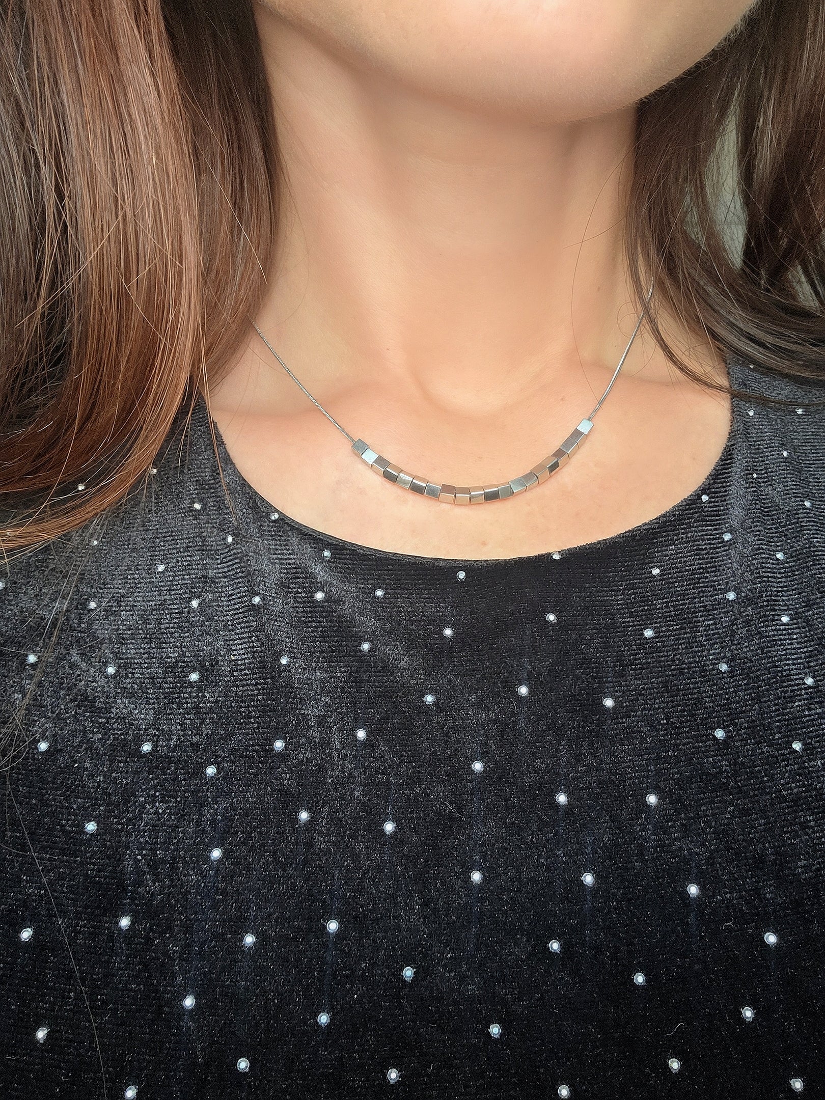 Geometric cube spinner pendant necklace on a polished gold-plated chain.