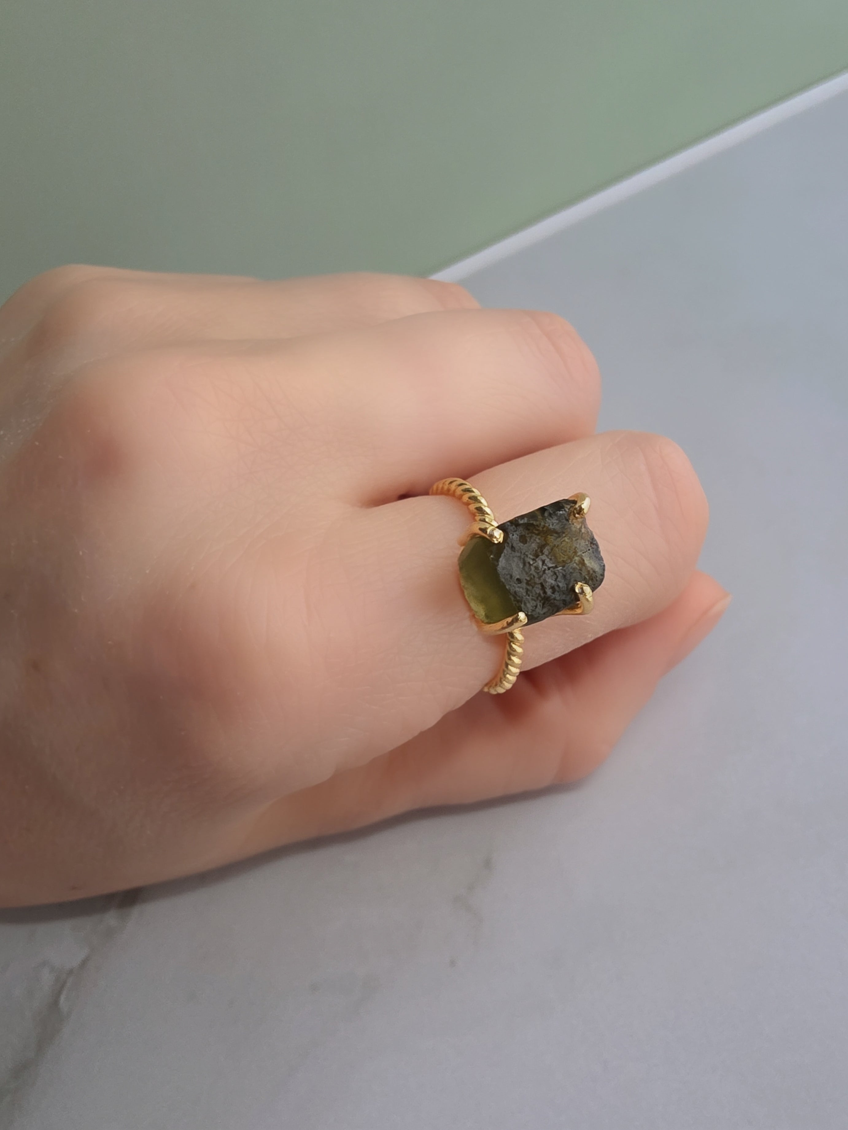 Elegant raw moldavite crystal ring featuring a natural green gemstone and adjustable gold-plated band.