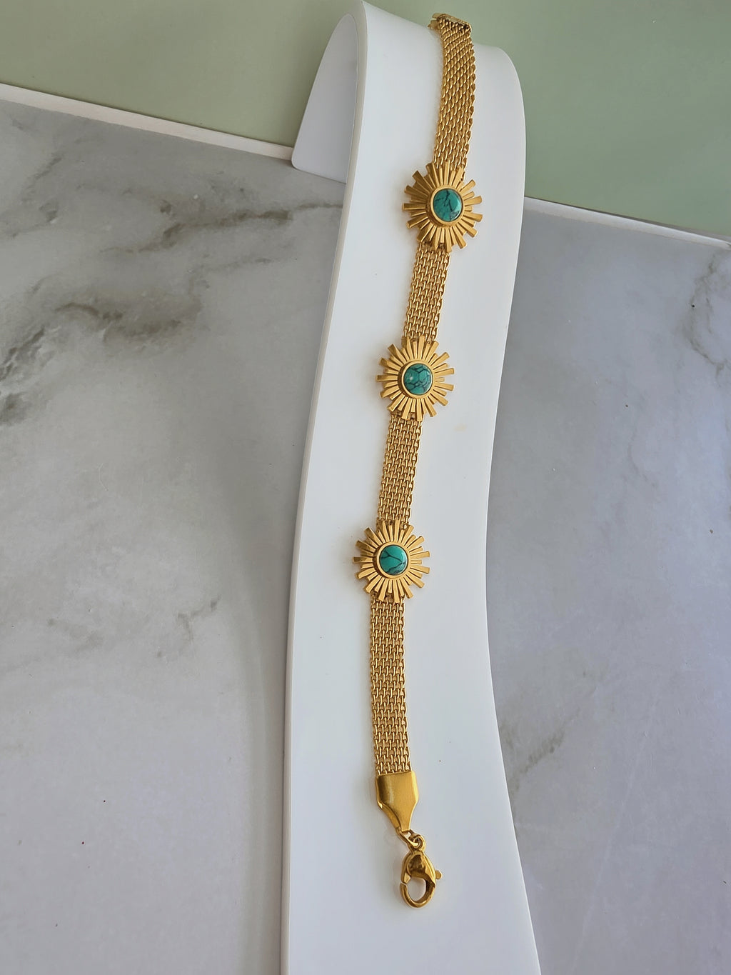 Adjustable sunflower bracelet with a turquoise-colored floral design.