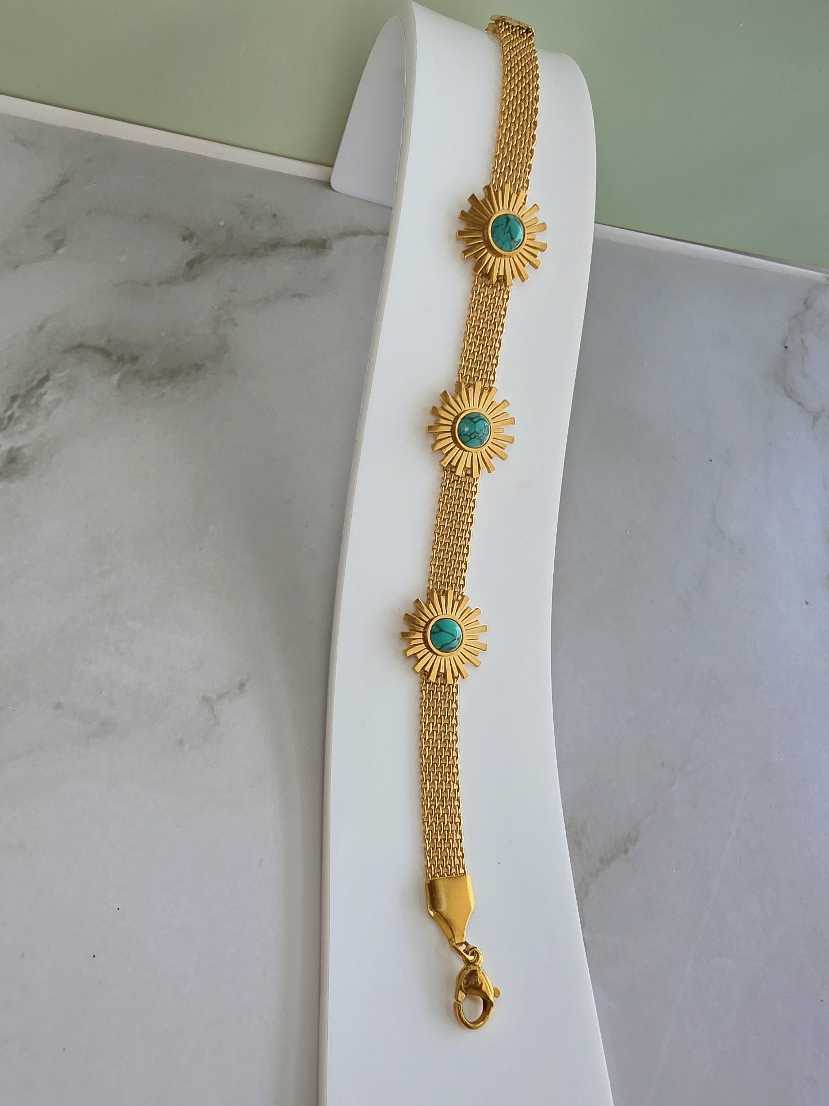 Adjustable sunflower bracelet with a turquoise-colored floral design.