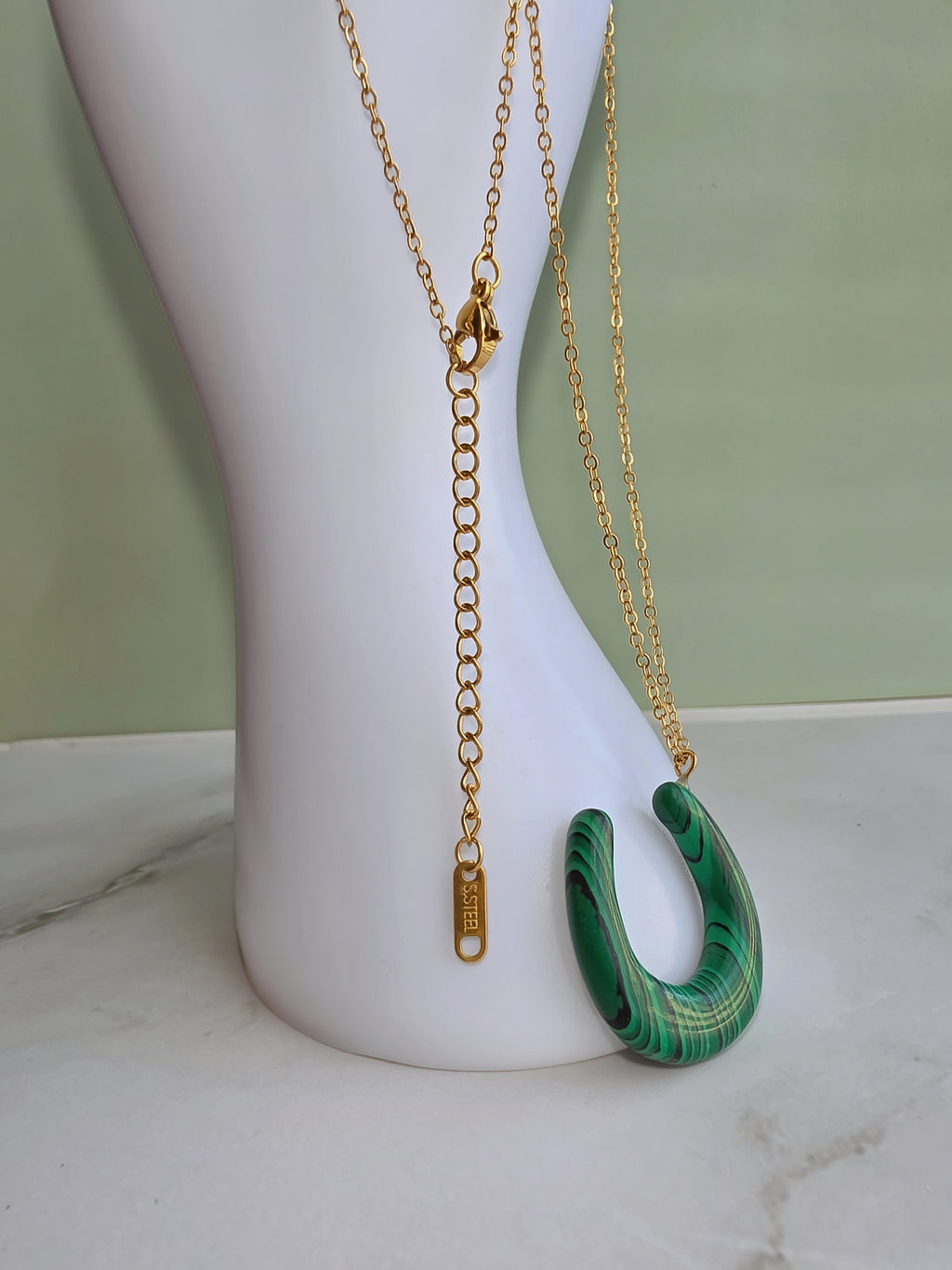 Gold malachite pendant necklace with a modern horseshoe design.