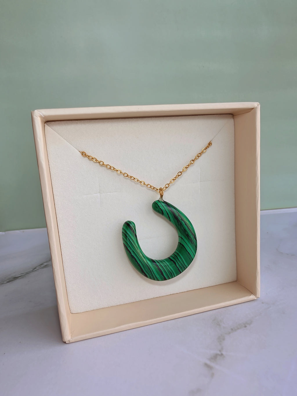Elegant lucky horseshoe necklace with a natural malachite pendant.