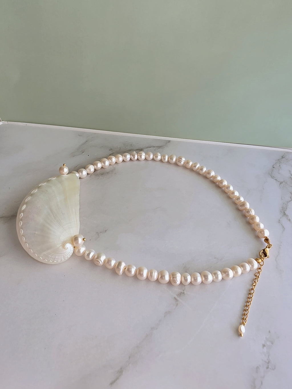 Elegant pearl necklace with a seashell pendant perfect for coastal outfits.