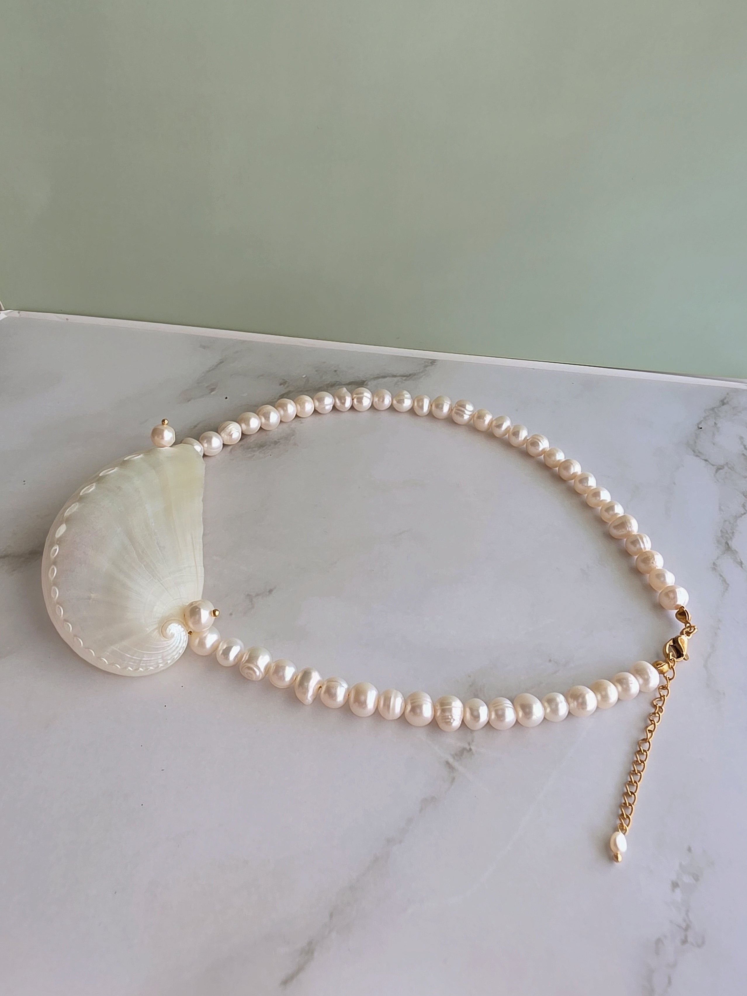 Elegant pearl necklace with a seashell pendant perfect for coastal outfits.