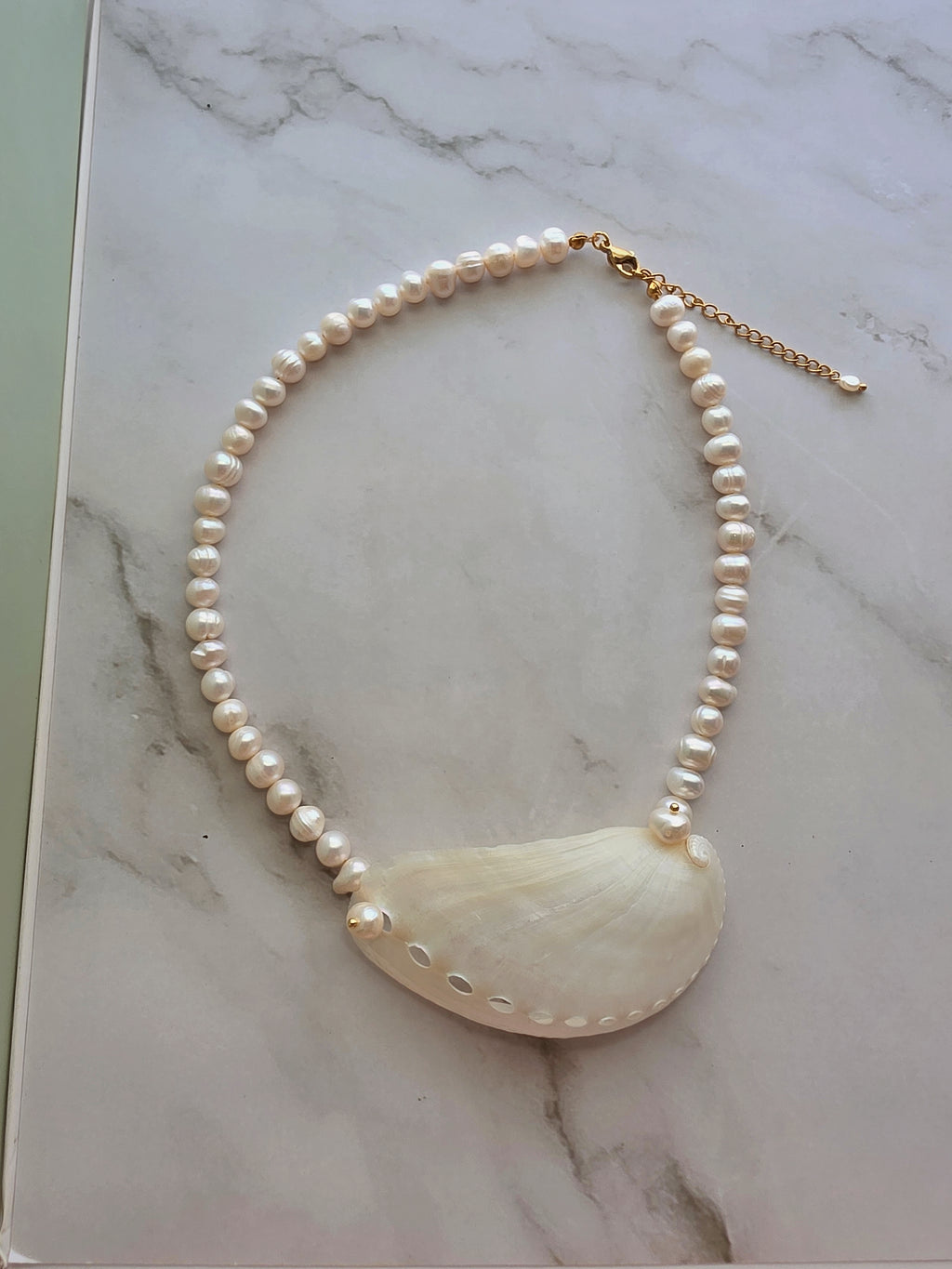 Freshwater pearl choker featuring a genuine seashell pendant for beach-inspired style.