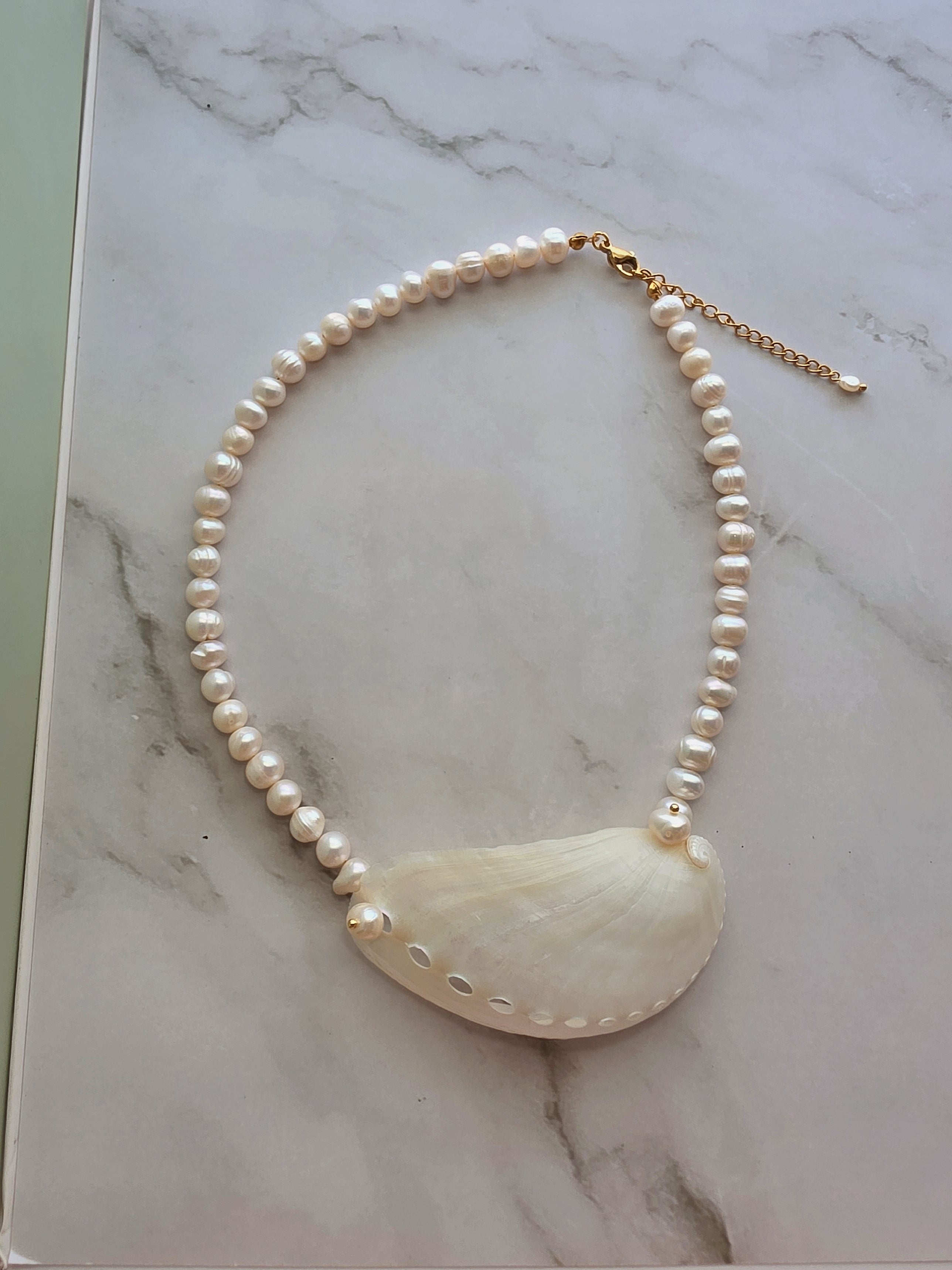 Freshwater pearl choker featuring a genuine seashell pendant for beach-inspired style.