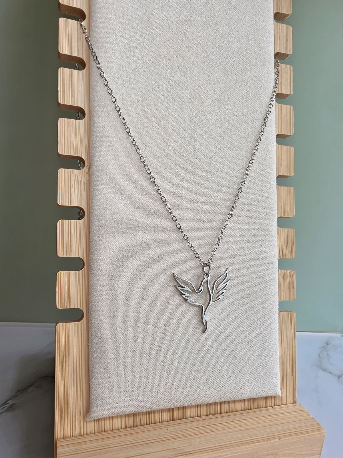 Silver stainless steel phoenix necklace with an openwork bird design.