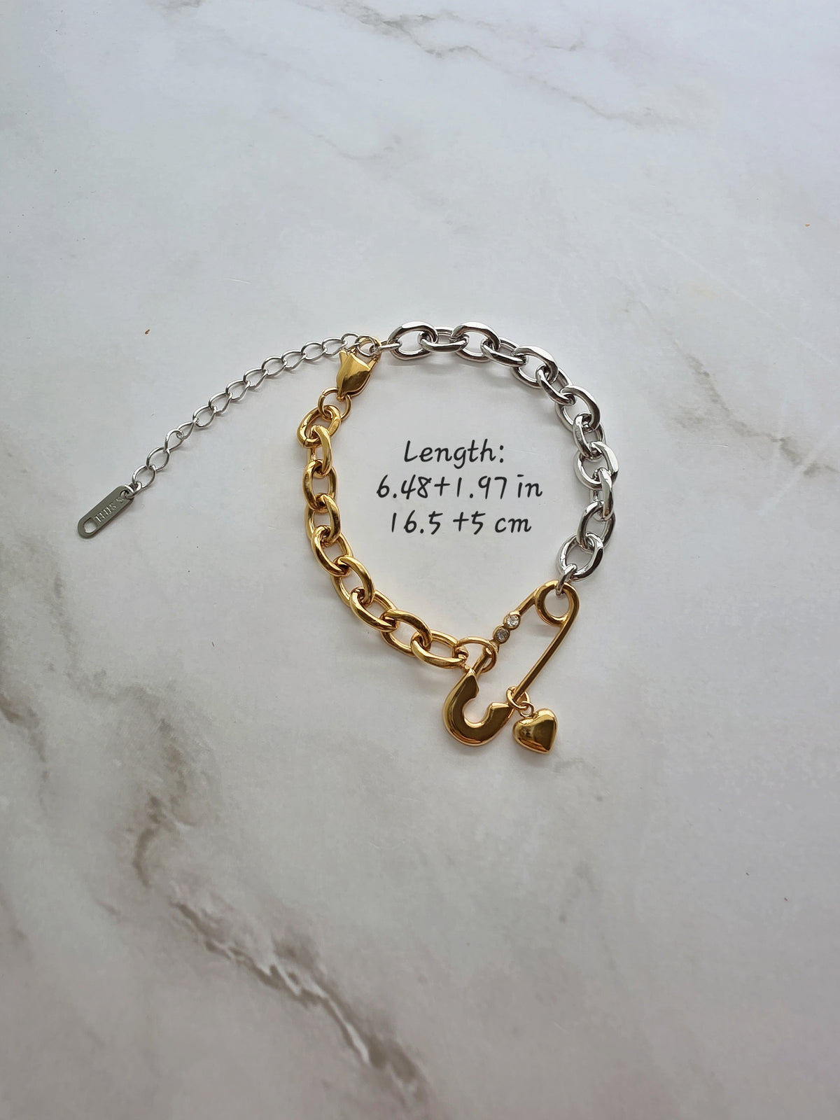 Two-tone stainless steel safety pin jewelry with a heart charm.