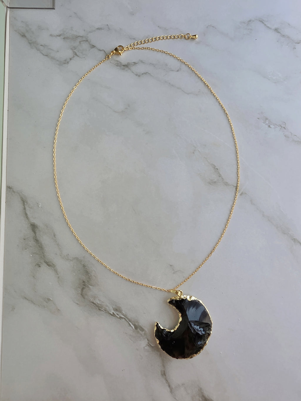 Elegant crescent moon necklace featuring a polished Obsidian pendant.