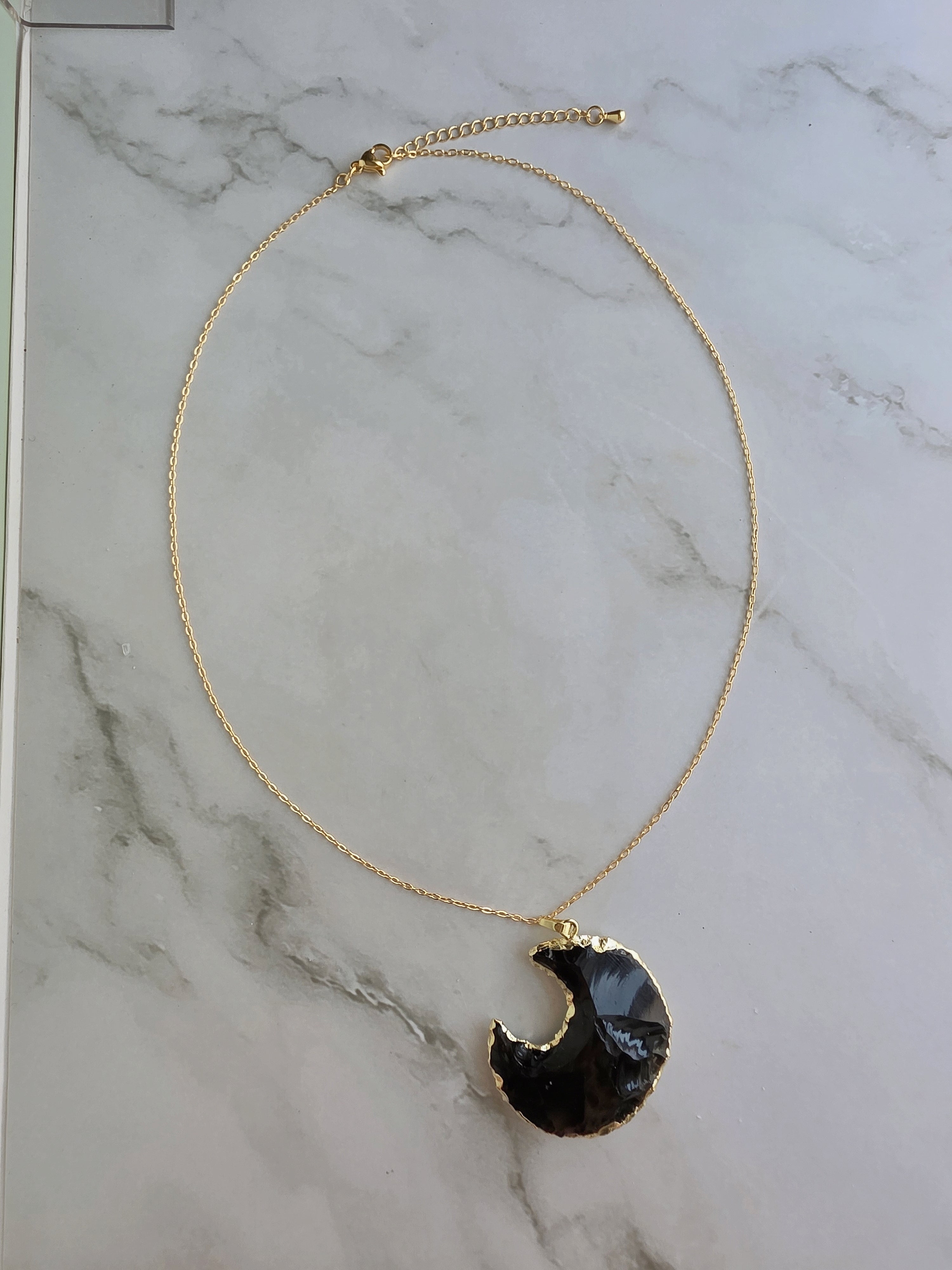 Elegant crescent moon necklace featuring a polished Obsidian pendant.