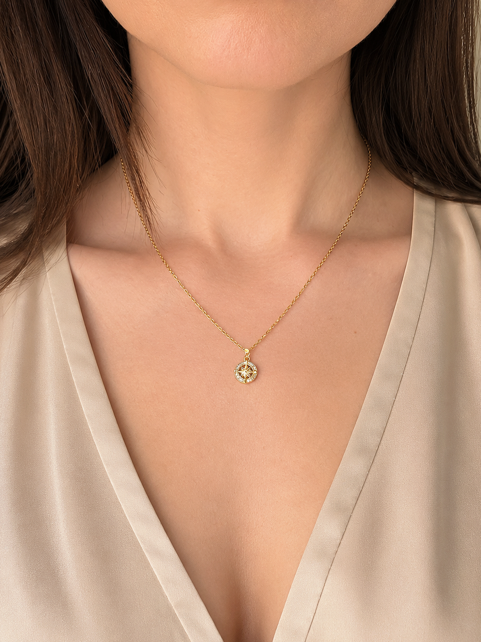 Gold compass necklace symbolizing guidance and adventure.