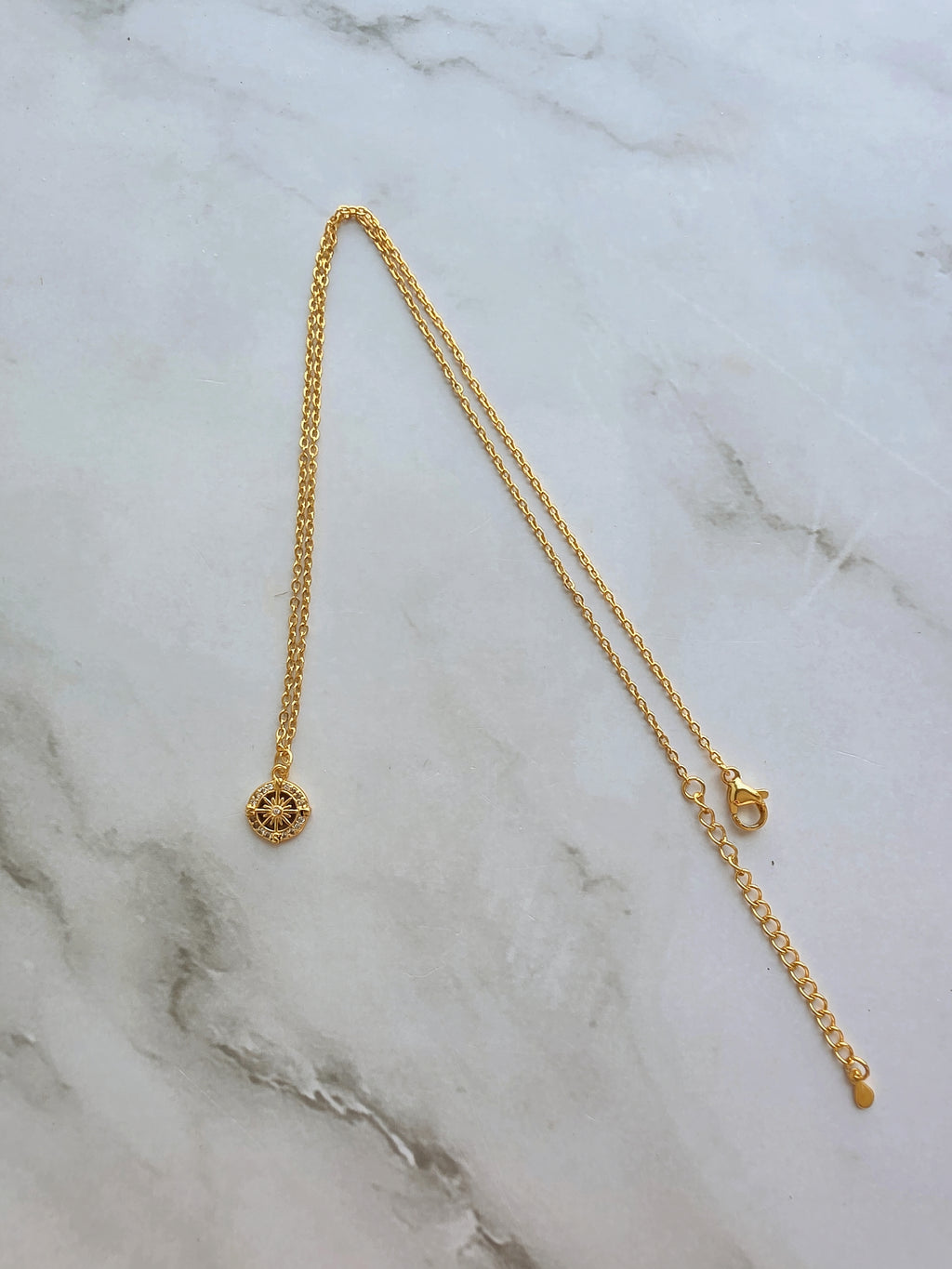 Elegant compass necklace with sparkling cubic zirconia.