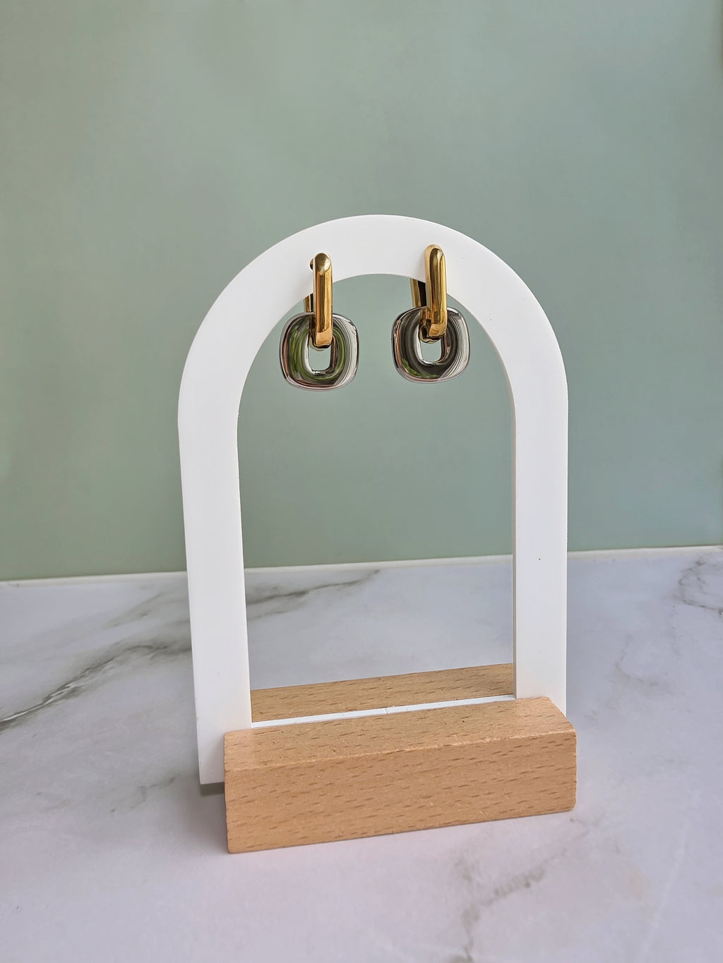 Non tarnish mixed metal earrings crafted from 18K gold-plated and silver stainless steel with a modern two-tone huggie hoop design.