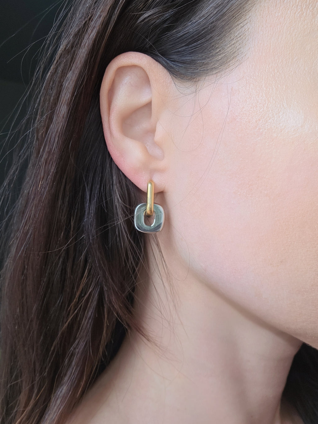 Non tarnish mixed metal earrings crafted from 18K gold-plated and silver stainless steel with a modern two-tone huggie hoop design.