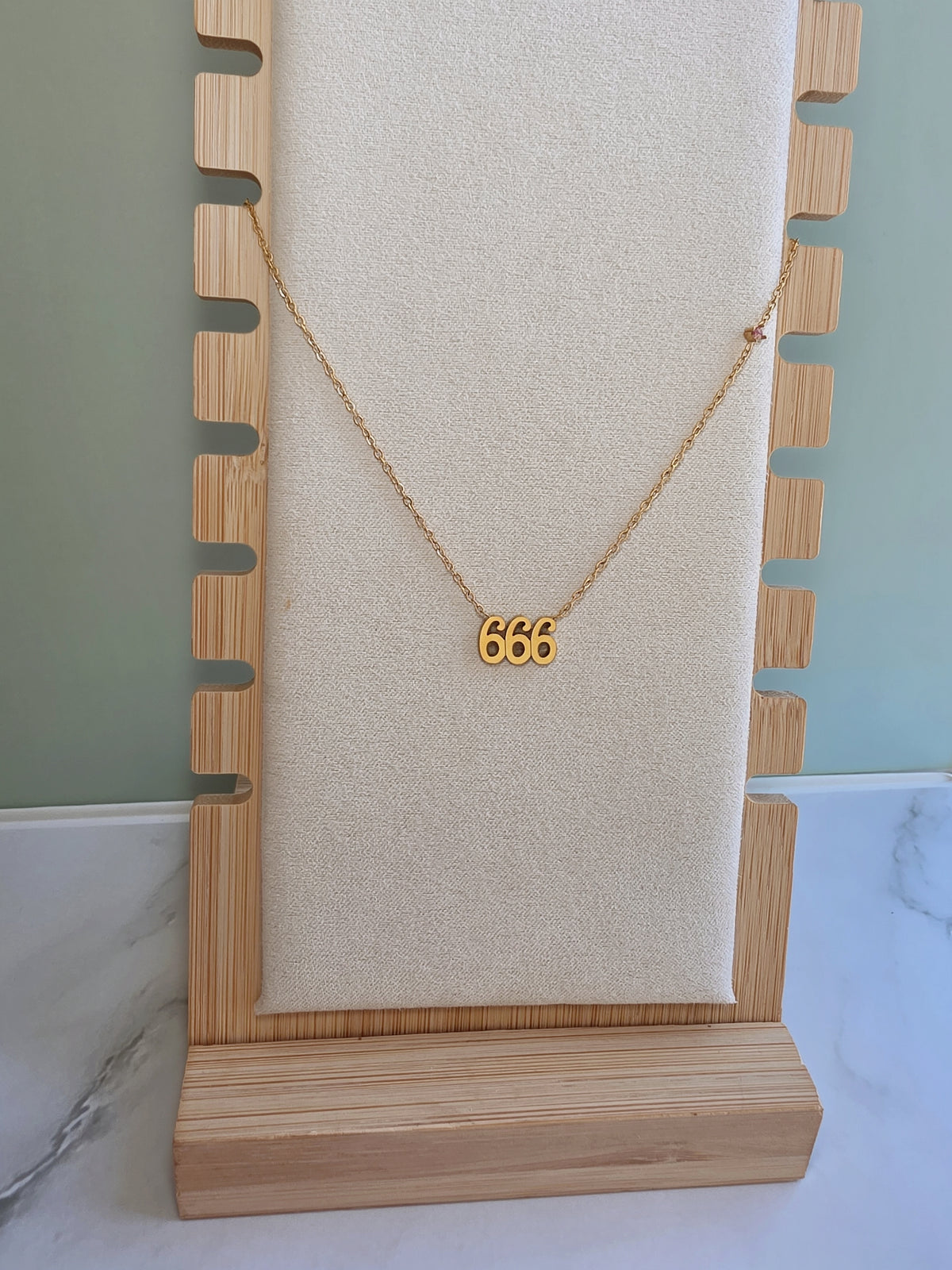 Gold angel number pendant necklace worn by a woman.