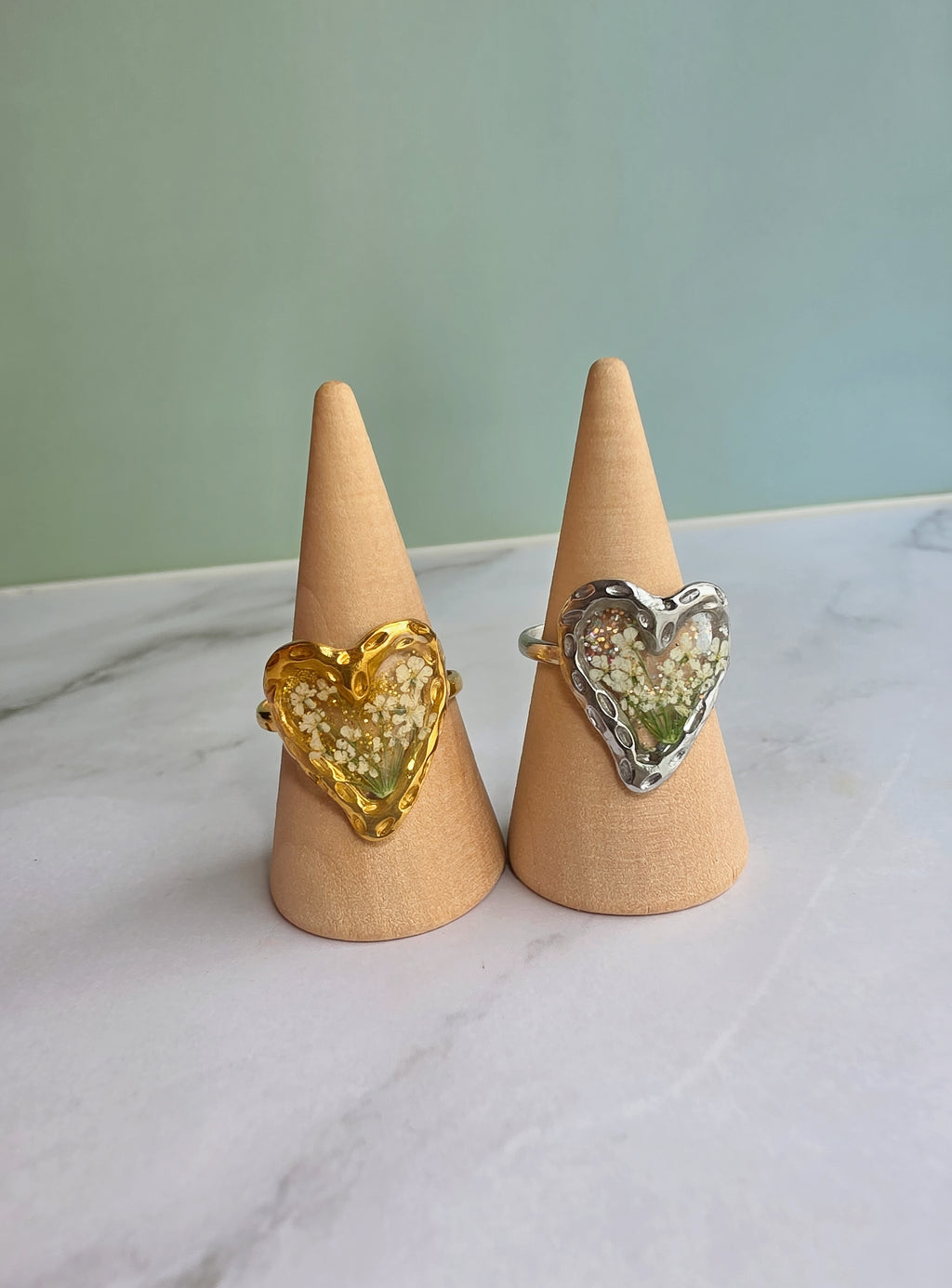 Gold heart ring with preserved flowers inside crystal-clear resin.