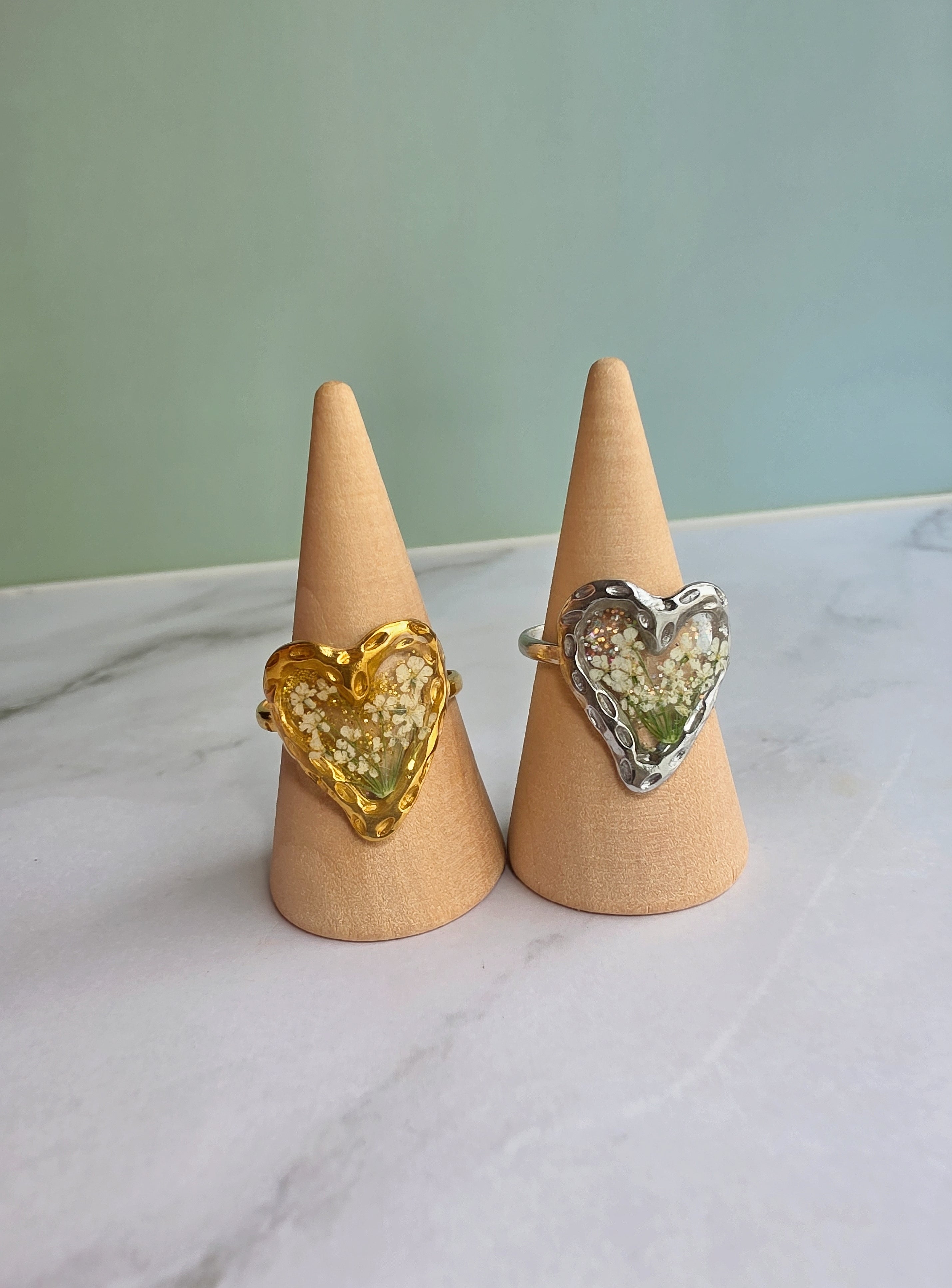 Gold heart ring with preserved flowers inside crystal-clear resin.