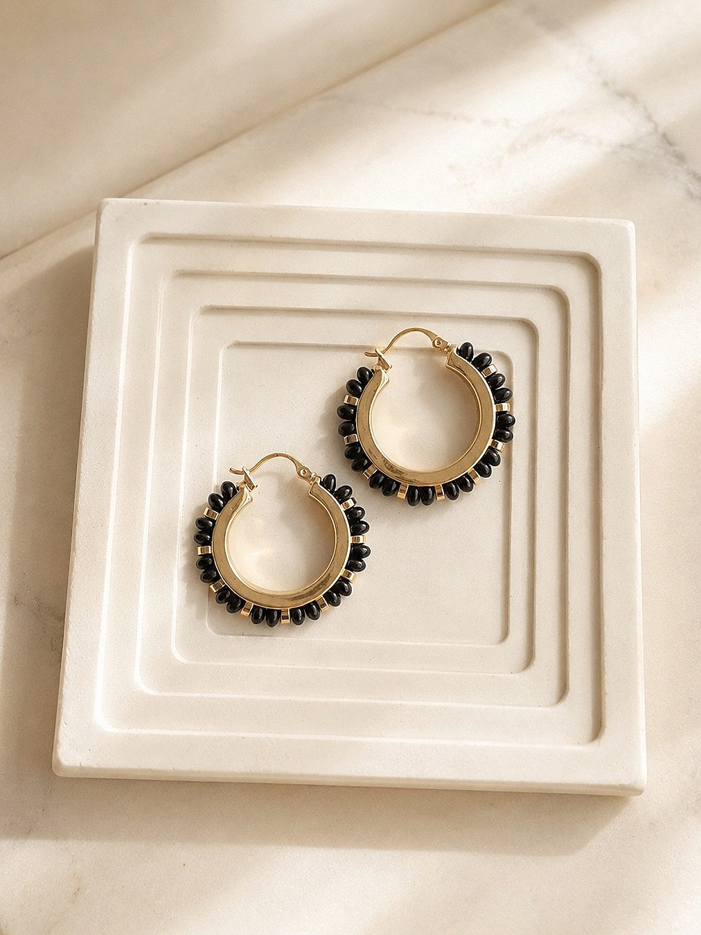 Black onyx beaded earrings on ivory boutique background