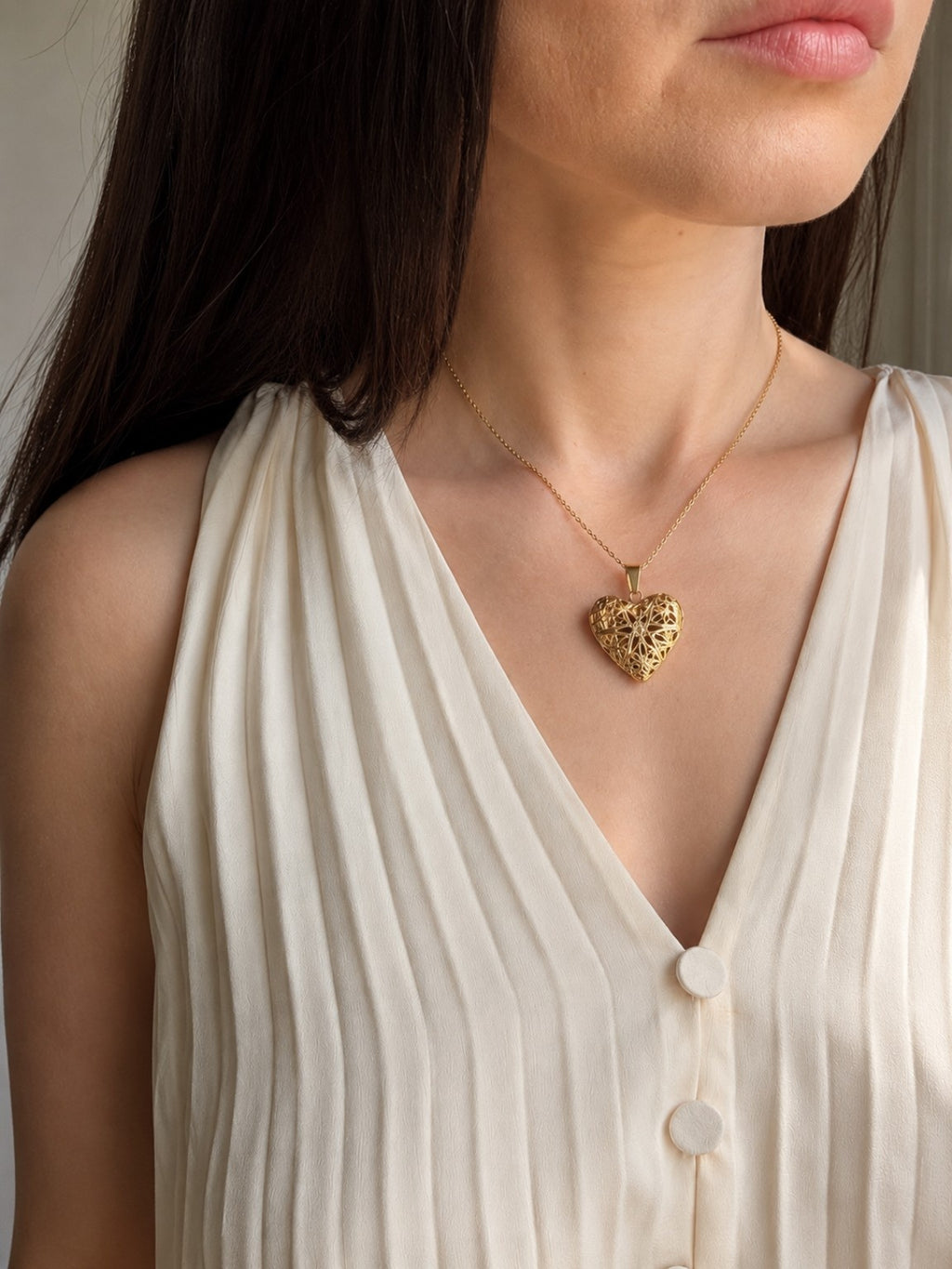 Heart locket necklace with an 18K gold-plated finish and intricate openwork design.