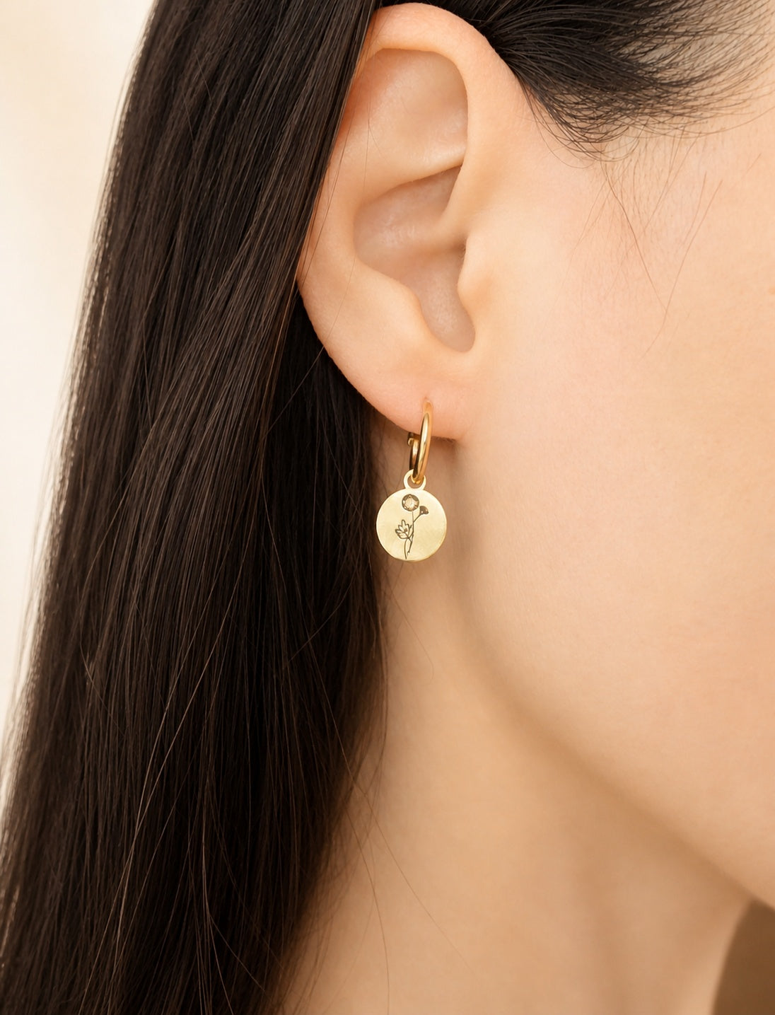 Dainty birth flower earrings with engraved charms on 18K gold-plated huggie hoops.