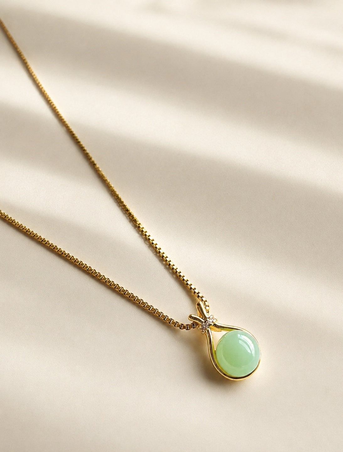 Green jade pendant necklace with a polished 14K gold-plated chain.