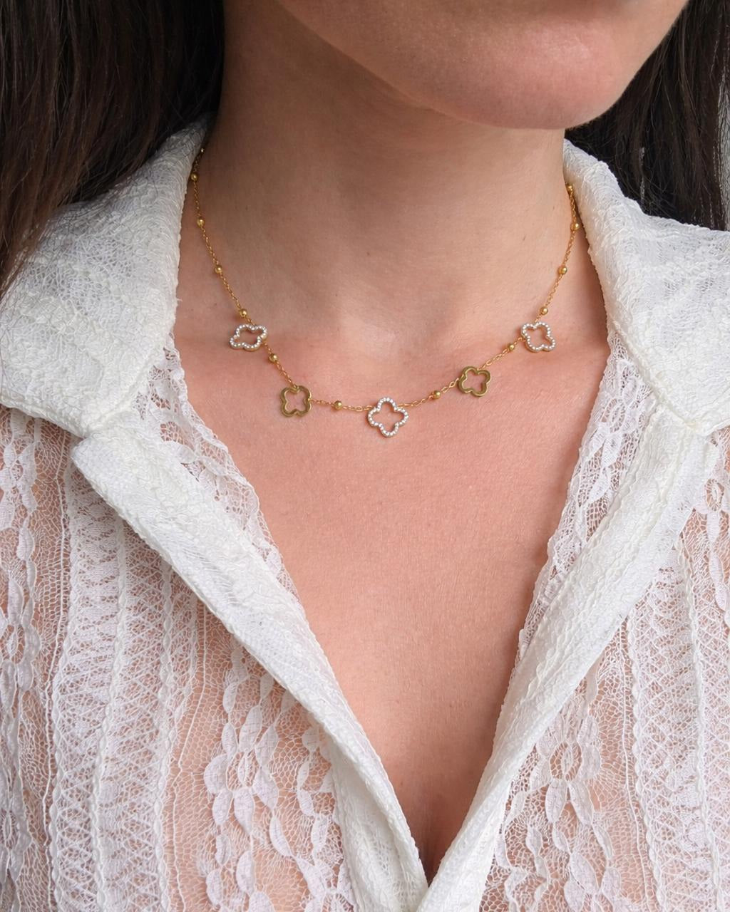 Layered gold necklace set featuring delicate clover motifs.