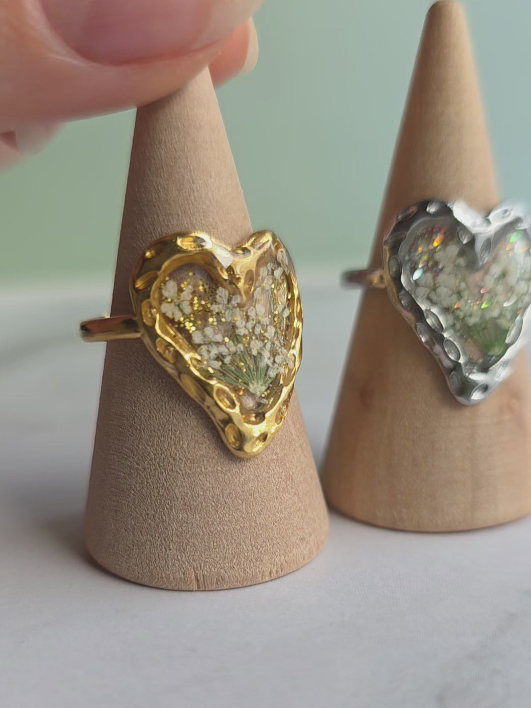 Handmade-style botanical resin ring with adjustable band and heart-shaped design.